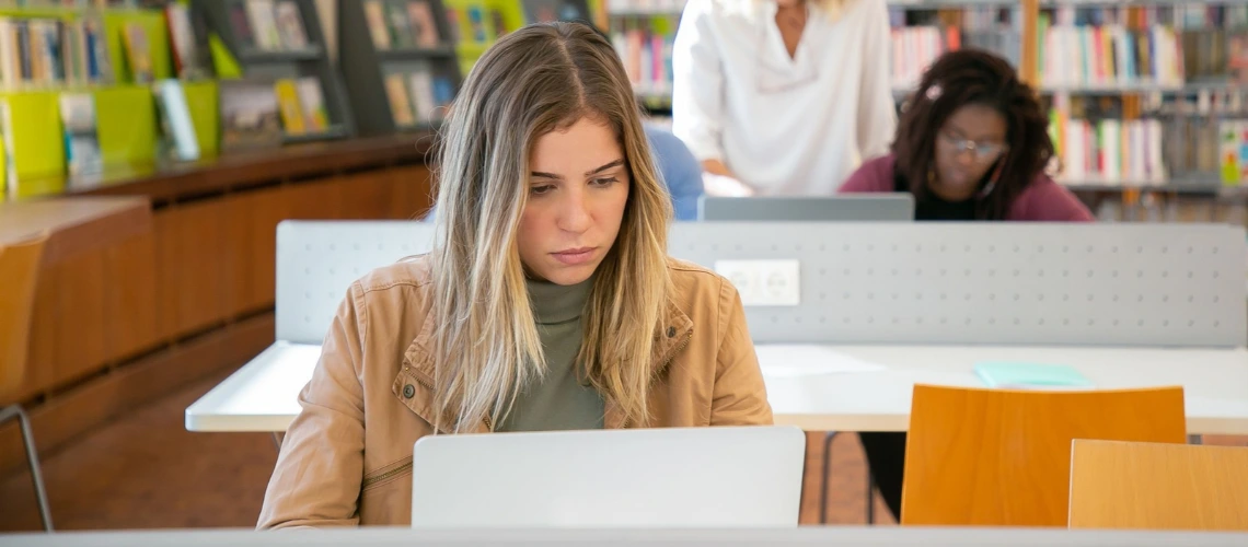 Student working on a laptop while writing her dissertation in APA format.