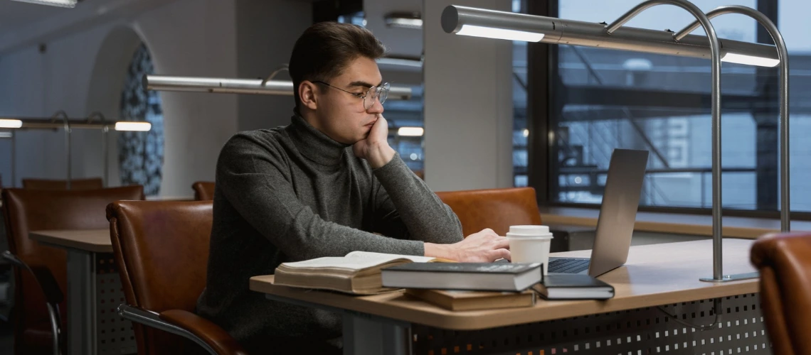 Student working on LaTeX thesis by publication on a laptop at a desk